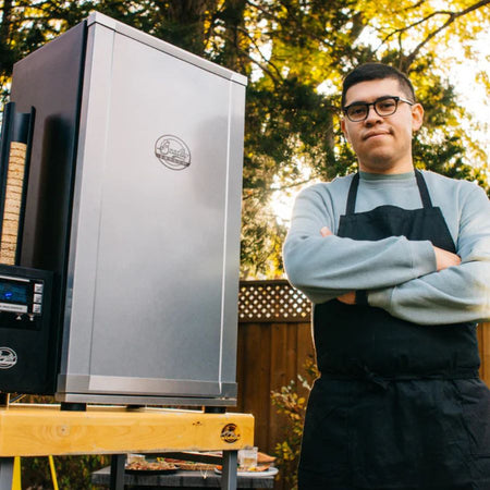 Man standing next to Bradley Digital 4-Rack Electric Smoker in backyard