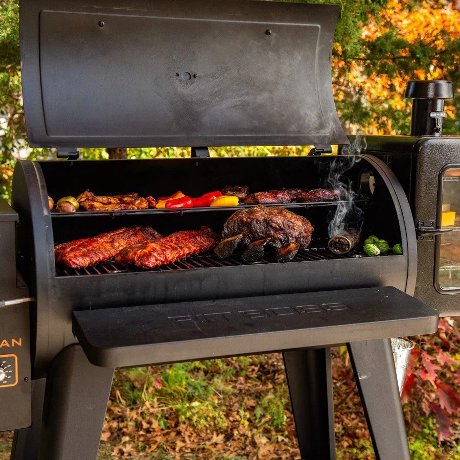 A-Maze-N 6" Tube Smoker, a cylindrical metal mesh tube filled with wood pellets, smoking on a grill