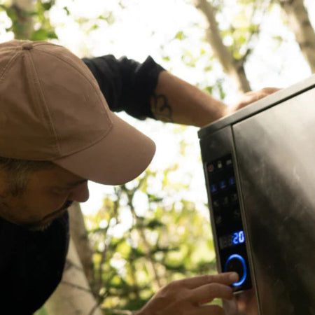 Close-up of a man adjusting the temperature on the digital control panel of the Bradley Smoker P10