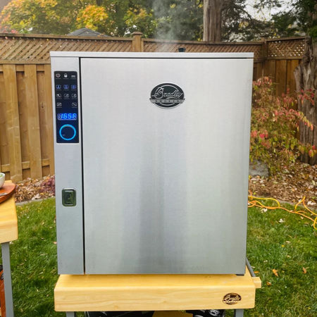 Bradley Smoker P10 Professional 4-Rack in a backyard setting with visible smoke coming out of the unit