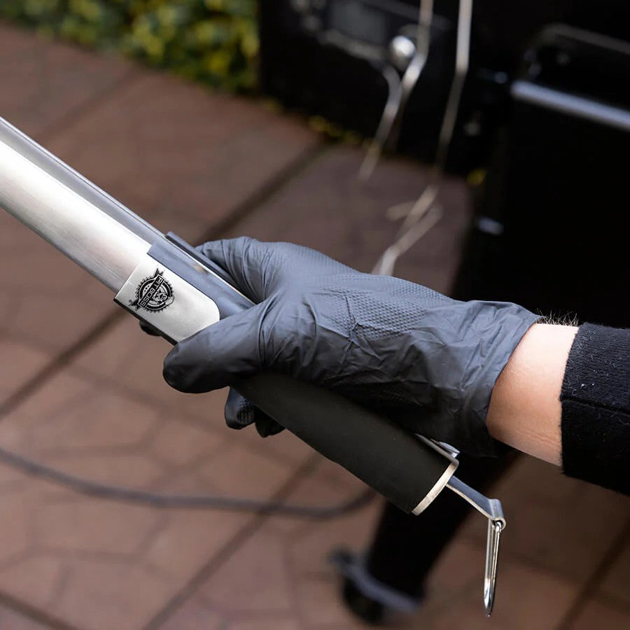 Close-up of a hand wearing a black Pit Boss disposable nitrile glove, holding a grilling tool