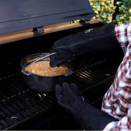 Pit Boss leather barbecue gloves, shown in use handling hot food on a grill