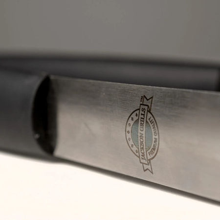 Close-up of Jackson Grills logo on stainless steel tongs