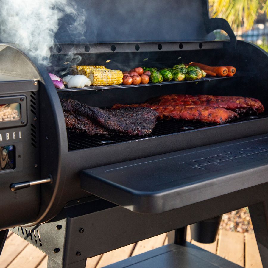 Louisiana Grills 1200 Black Label Pellet Grill in use, grilling meat, corn, and vegetables with flavorful wood pellet smoke.