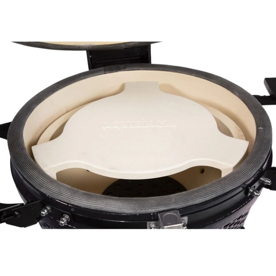 Close-up view of the heat deflector inside the Louisiana Grills 24" Ceramic Kamado Charcoal Grill, designed to regulate indirect cooking and smoking.