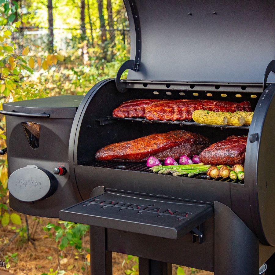 Louisiana Grills Founders Series Premier 800 Pellet Grill in action, cooking ribs, brisket, and vegetables with wood pellet smoke.