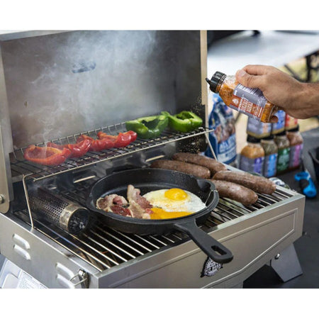 Pit Boss 12-inch Cast Iron Deep Skillet cooking food on a grill, showing the lid resting next to it