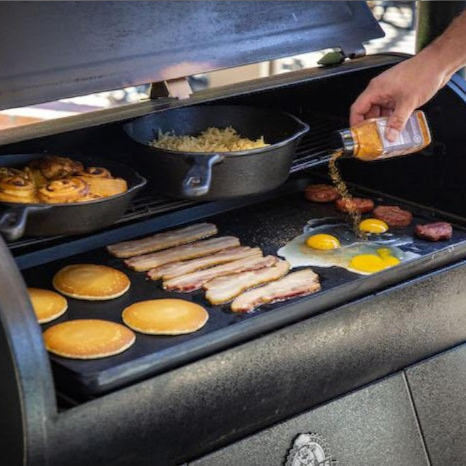 Breakfast food, including bacon and eggs, cooking on a Pit Boss 14" x 28" Cast Iron Griddle