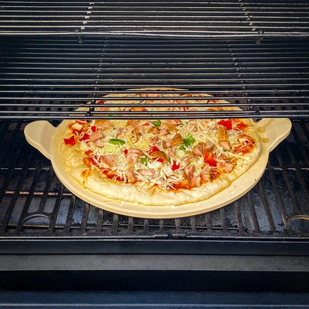 A Pit Boss 15-inch ceramic pizza stone with a golden-crusted pizza inside a grill