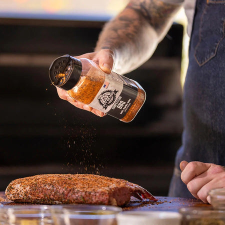 Pit Boss Competition BBQ Rub bottle on a wooden cutting board with meat