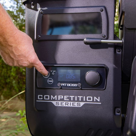 Close-up of the digital control panel on the Pit Boss Competition Series 1600 Wood Pellet Grill, with a person adjusting the settings.