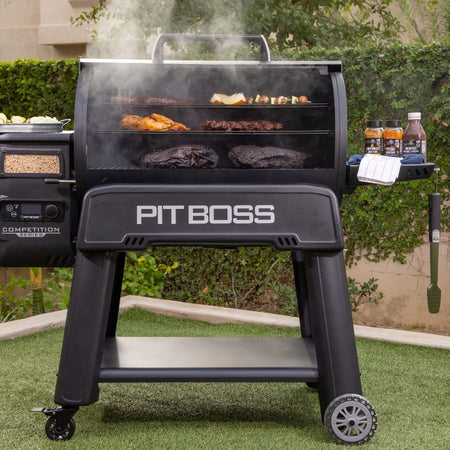 Pit Boss Competition Series 1600 Wood Pellet Grill in action, cooking a variety of meats and vegetables with smoke rising from the grill.