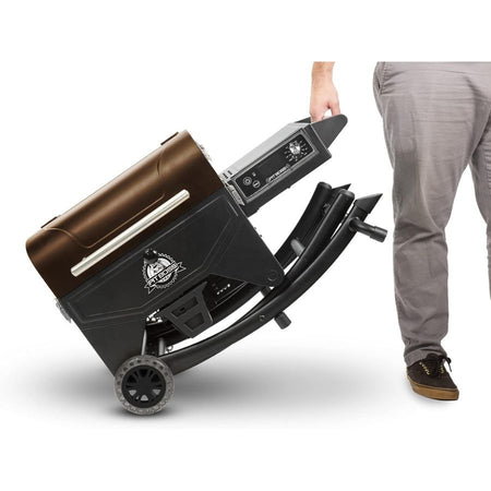Man rolling Pit Boss Mahogany 260 Portable Wood Pellet Grill using side handle and wheels