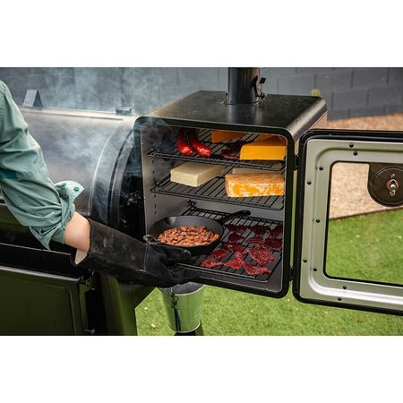 A close-up of a Pit Boss Side Smoker Attachment in use, with smoke gently rising
