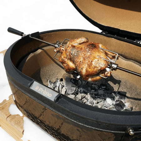 The Primo Ceramic Grills Oval Rotisserie Kit installed on a ceramic grill, showing it in use